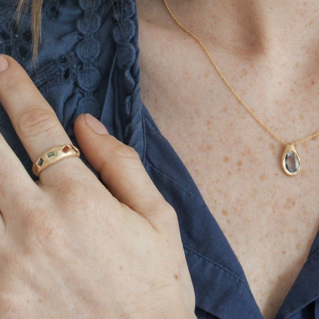 Model wearing handmade baguette rainbow sapphire ring in 18kt gold.