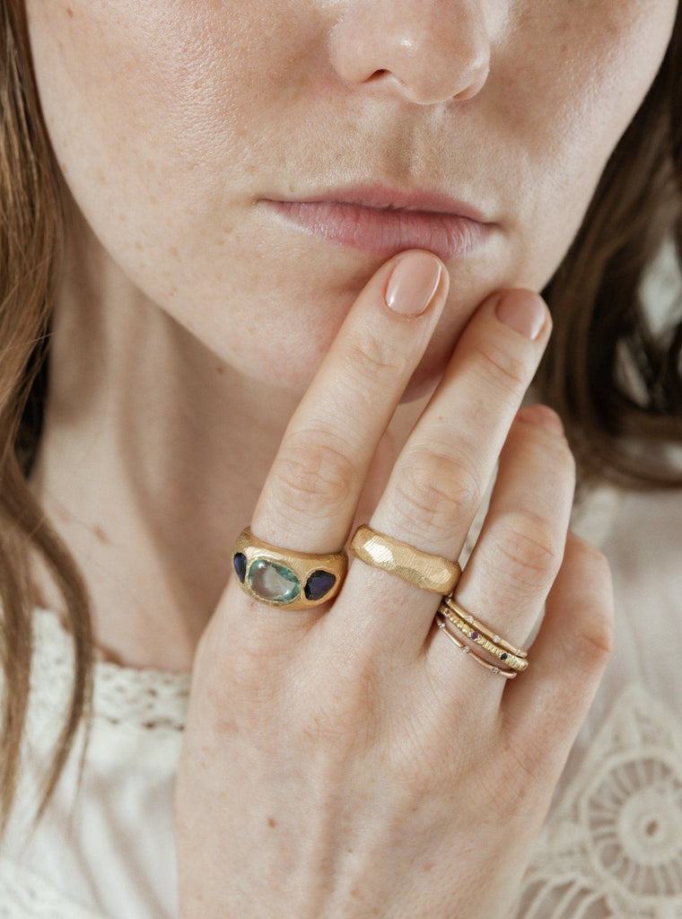 Handmade wedding band in 18kt gold with a 6mm width and hand carved texture. Also wearing a sapphire ring and stacking bands.